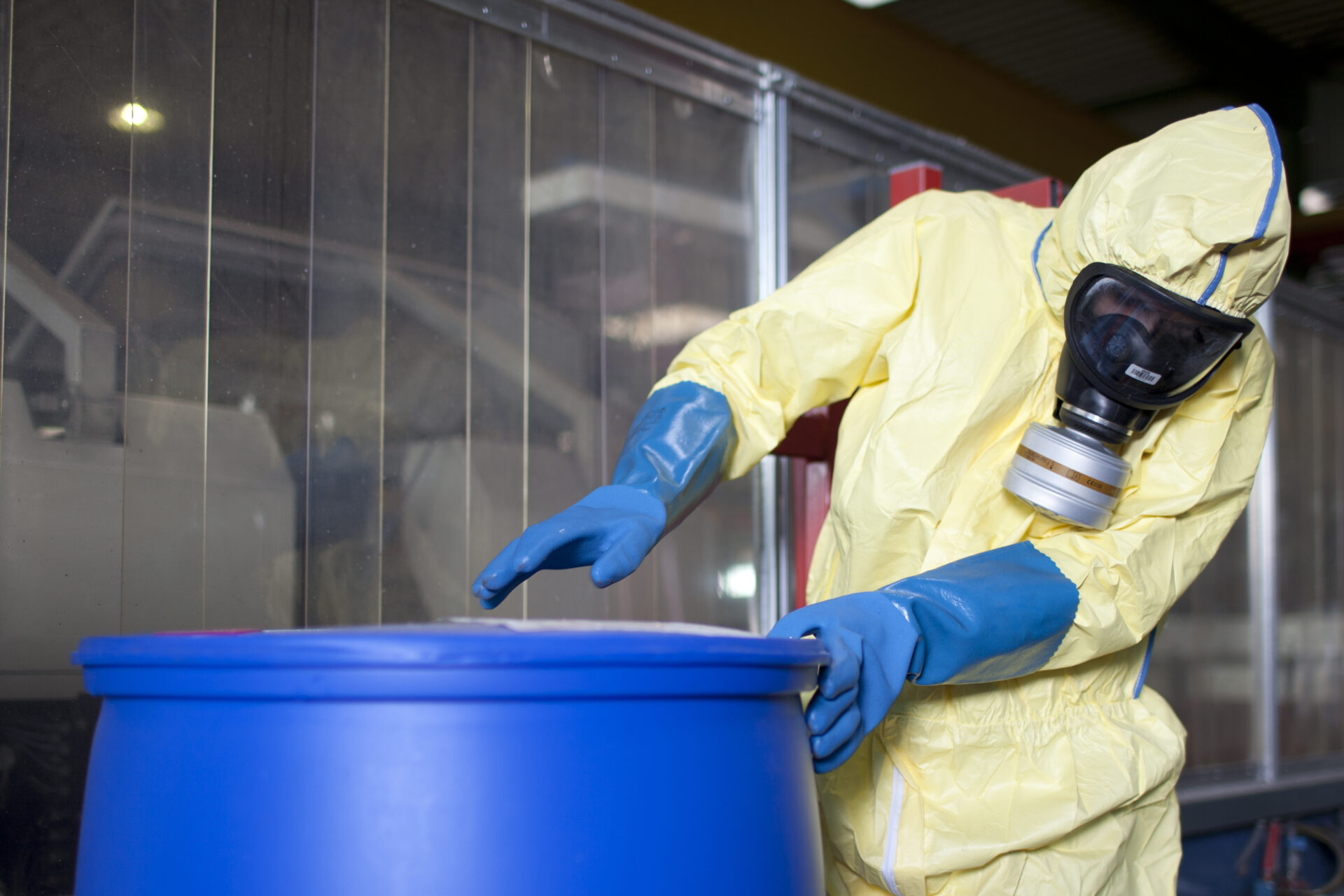 Person in hazmat suit handling drum.