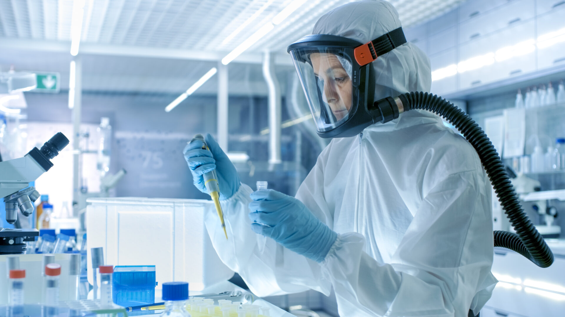 Scientist in lab coat using pipette.